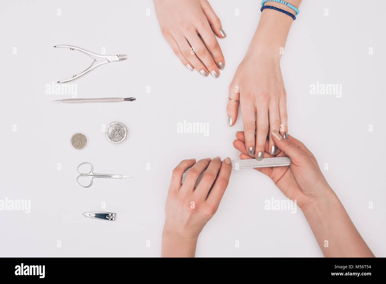 Zugeschnittenes Bild von Maniküre feilen Nägel an Kunden mit Nagelfeile isoliert auf weißem Stockfoto