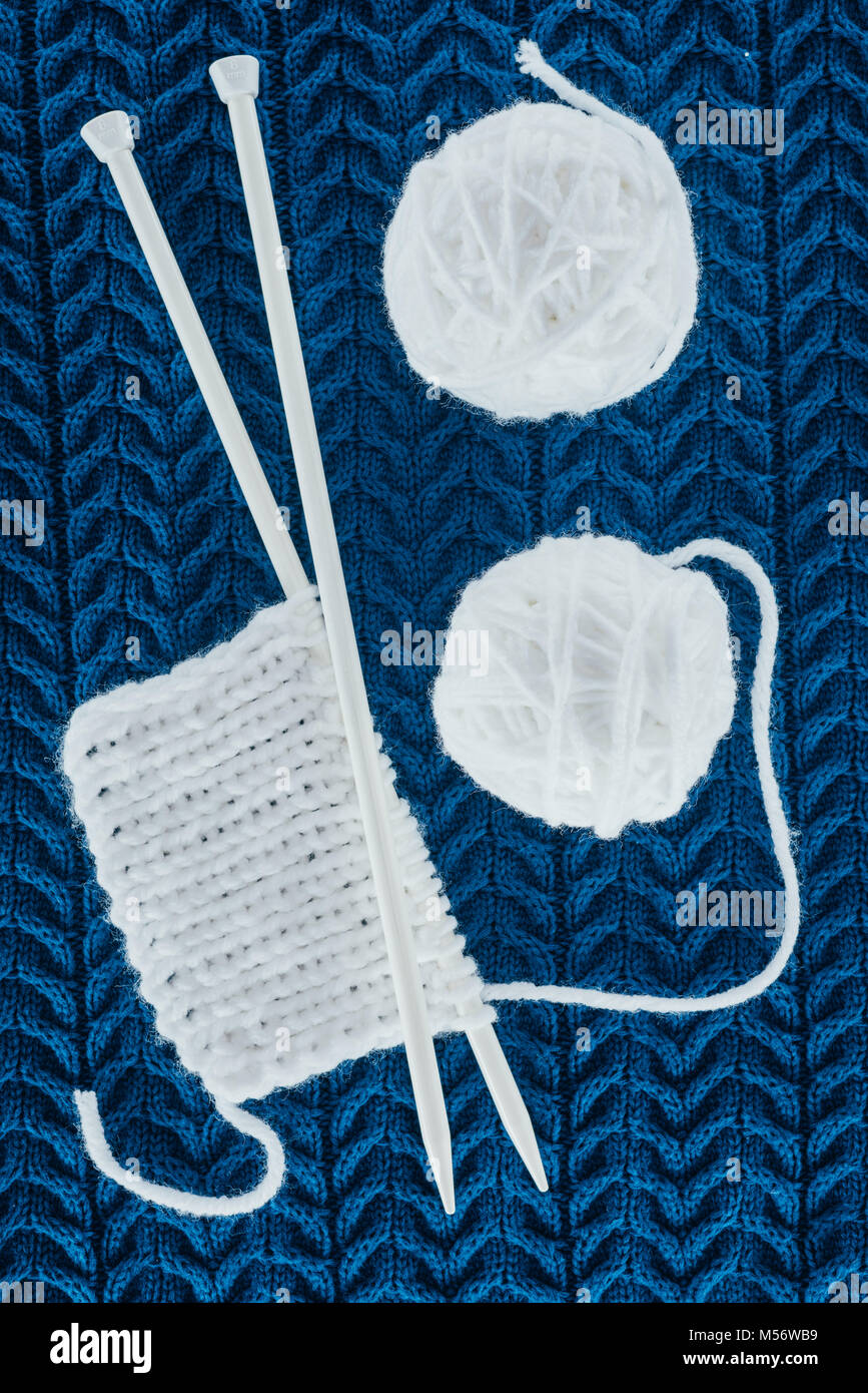 Blick von oben auf die weiße Kugeln Garn und Stricknadeln auf Blau stricken Stockfoto
