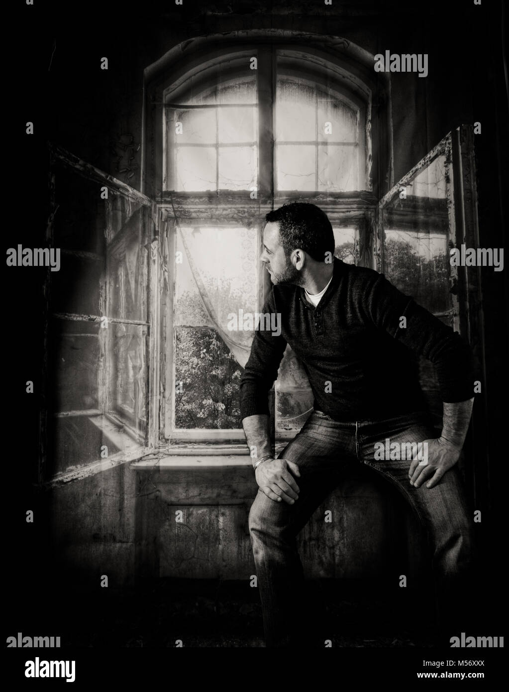 Ein studio Schießen von Wiltshire Fotograf Claire Allen von einem männlichen sitzen auf einer Fensterbank Blick aus dem Fenster.. Stockfoto