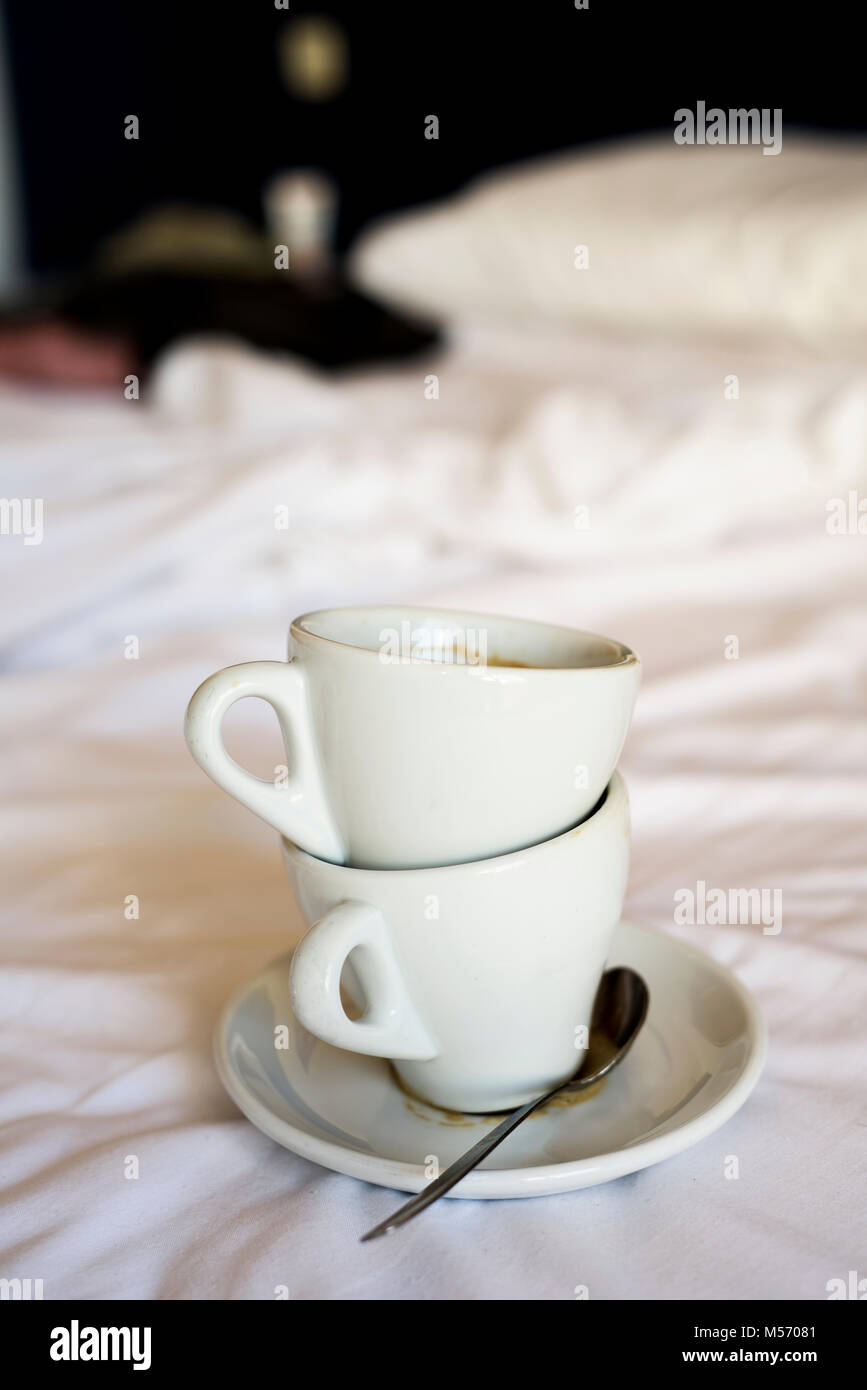 Zwei weiße Keramik leere Tassen Kaffee auf dem weißen Blatt ungemachten Bett Stockfoto