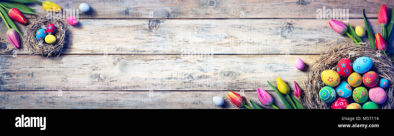 Tulpen und bemalte Eier in Nester auf Vintage Plank Stockfoto