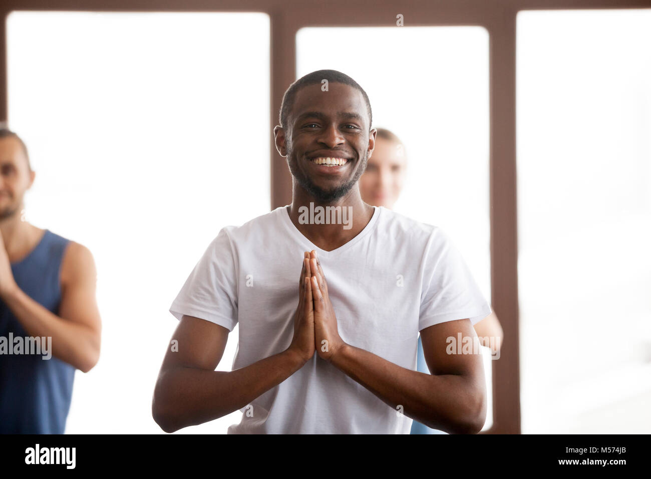 Lächelnd african-american man Hände halten in Namaste an die Gruppe t Stockfoto