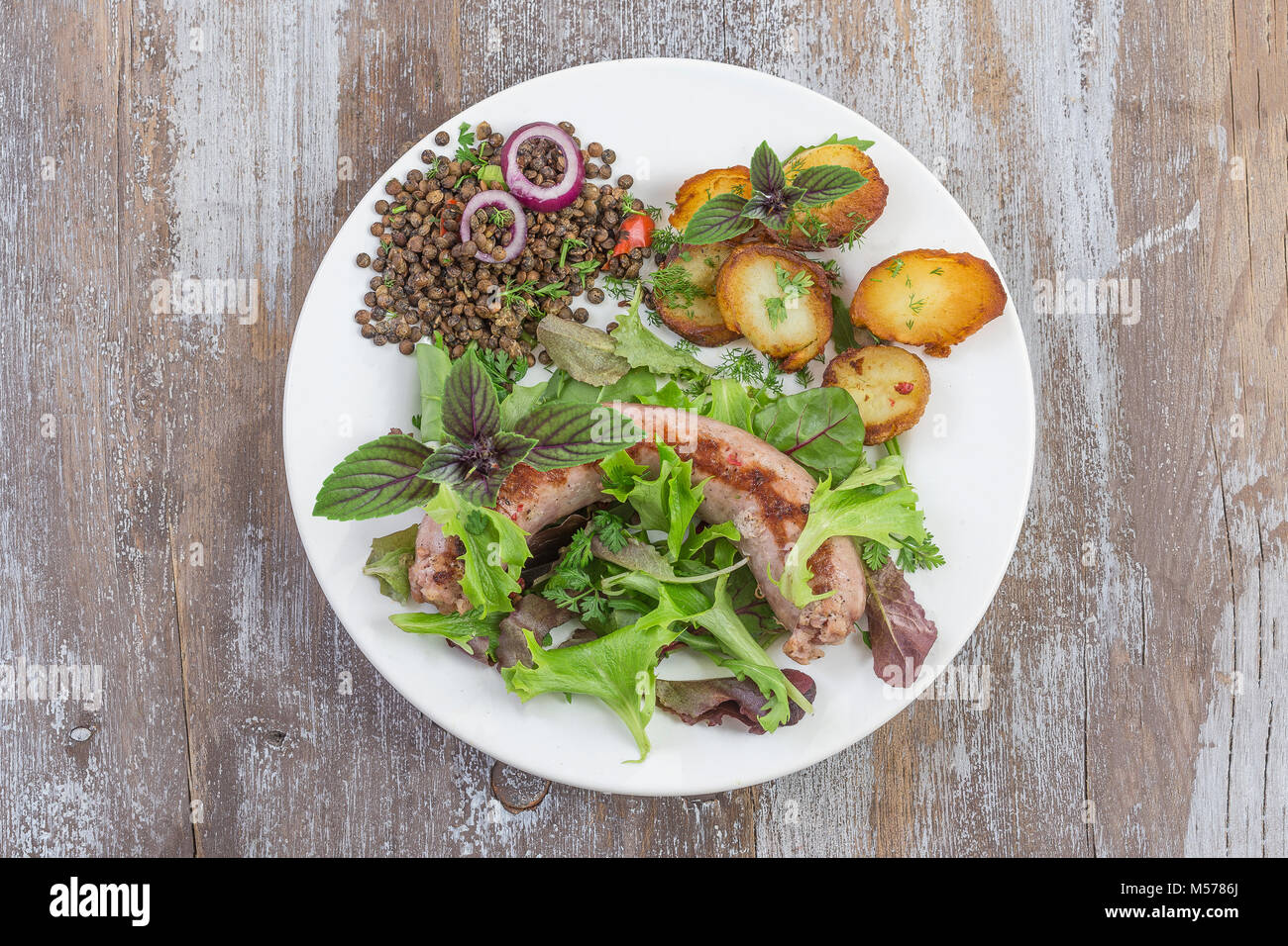 Frankreich Toulouse Wurst vom Grill mit gebratenen potatoaes und Salat und Linsen auf alten hölzernen Hintergrund Stockfoto