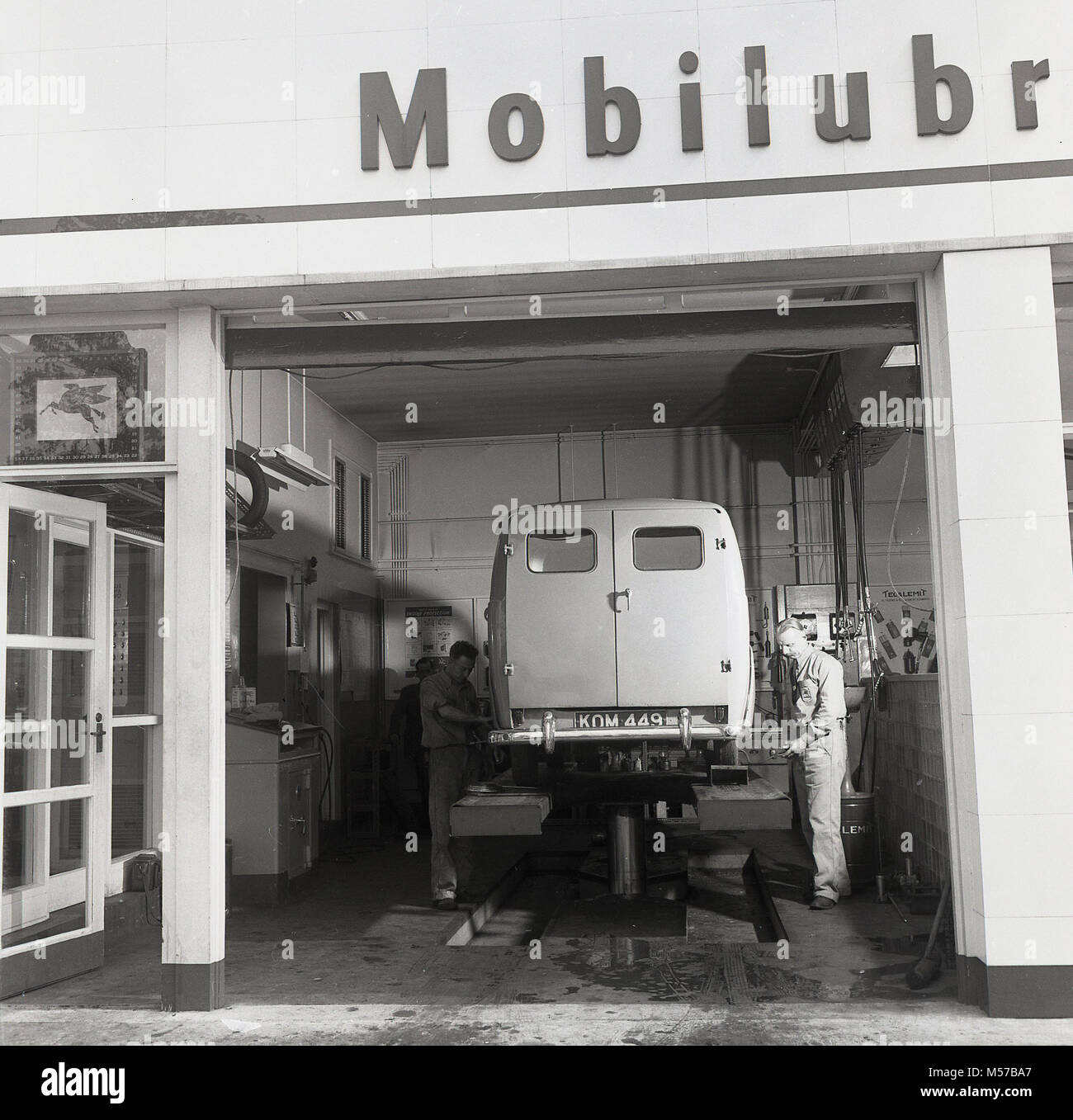 1950, historische, Mobil motor Mechanik Wartung einer Van innerhalb einer Mobilgas Garage Werkstatt, England, UK. Stockfoto