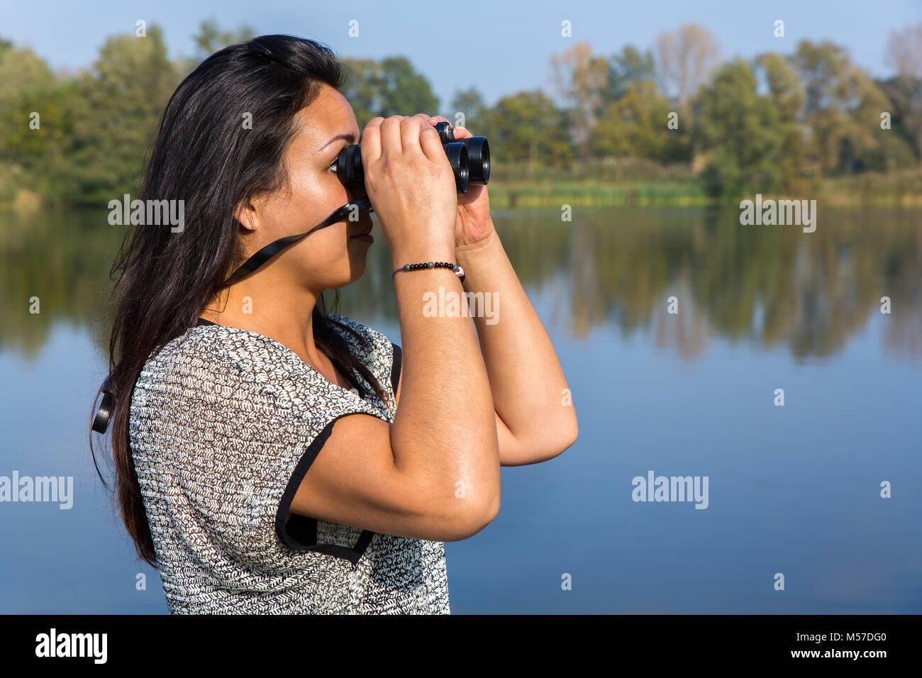 Frau auf der Suche durchs Fernglas am Wasser Stockfoto