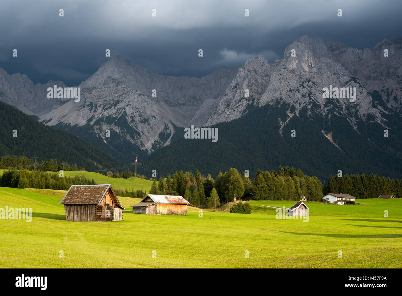 Landhäuser auf grünem Gras gegen Berg unter niedrigen Cloud Stockfoto