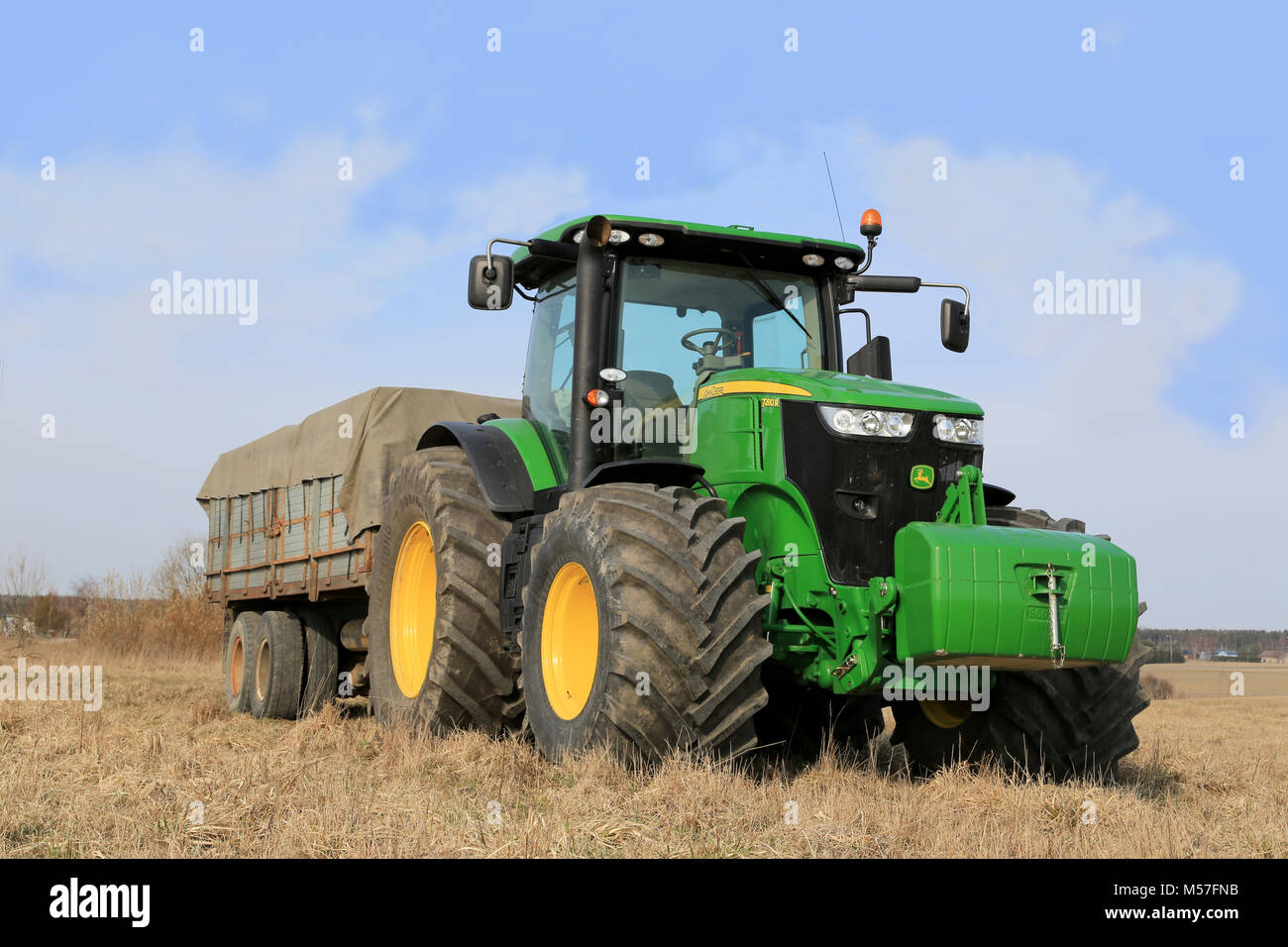 SALO, Finnland - 19 April, 2014: John Deere 7280 R Traktoren und landwirtschaftliche Anhänger von Feld. Deere kündigt Zwischenbericht 2. Das Ergebnis von $ 981 Millionen. Stockfoto