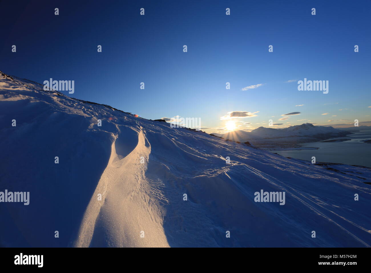 Sun Burst über Berg, Snow Drift Vordergrund Stockfoto