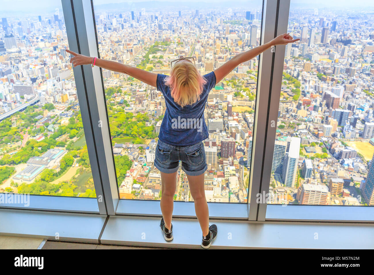 Luftbild Skyline von Osaka in Japan. Reise und Tourismus Asien Konzept. Junge kaukasier touristische Frau mit offenen Armen in Osaka Stadtbild von der Aussichtsplattform. Stockfoto