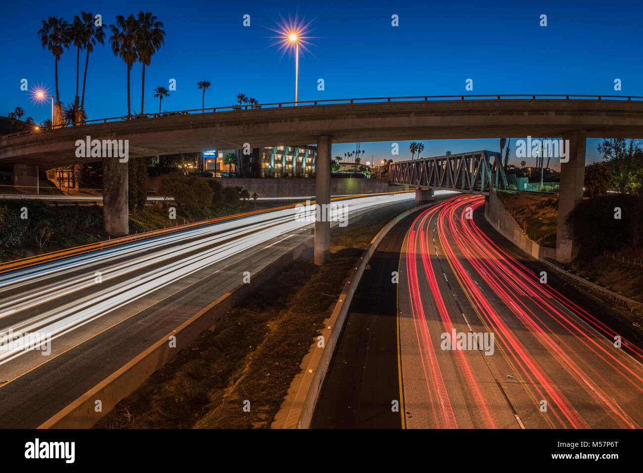 Dawn brechen den blauen Himmel und Fahrzeug Scheinwerfer Streifen auf beiden Seiten der Autobahn Autobahn. Stockfoto
