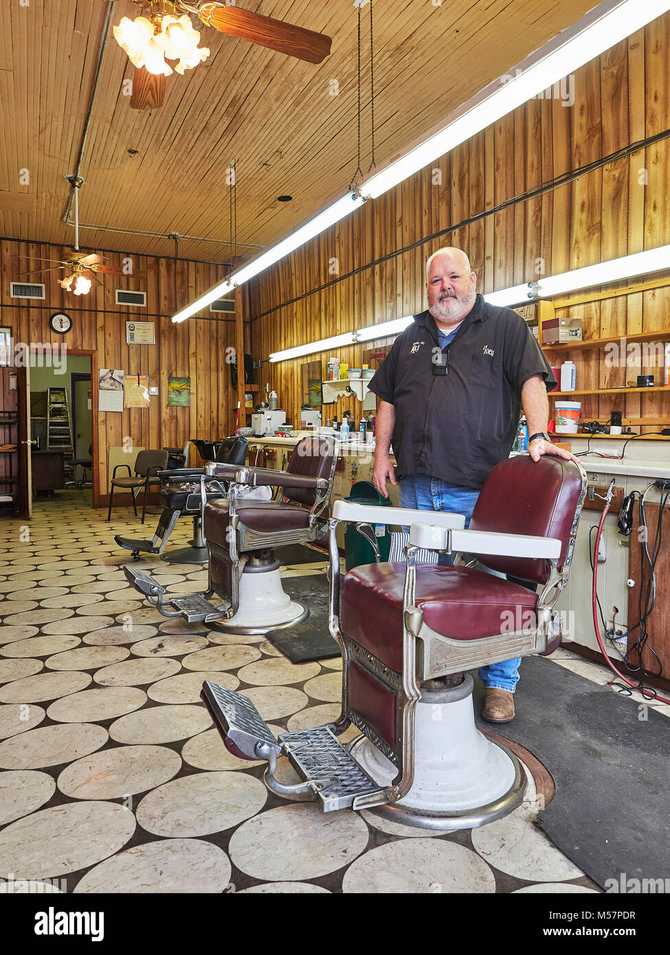 Kleine Stadt männlich Friseur stand neben einer alten, antiken Friseur Stuhl in einem vintage Friseur in Prattville, Alabama, USA. Stockfoto