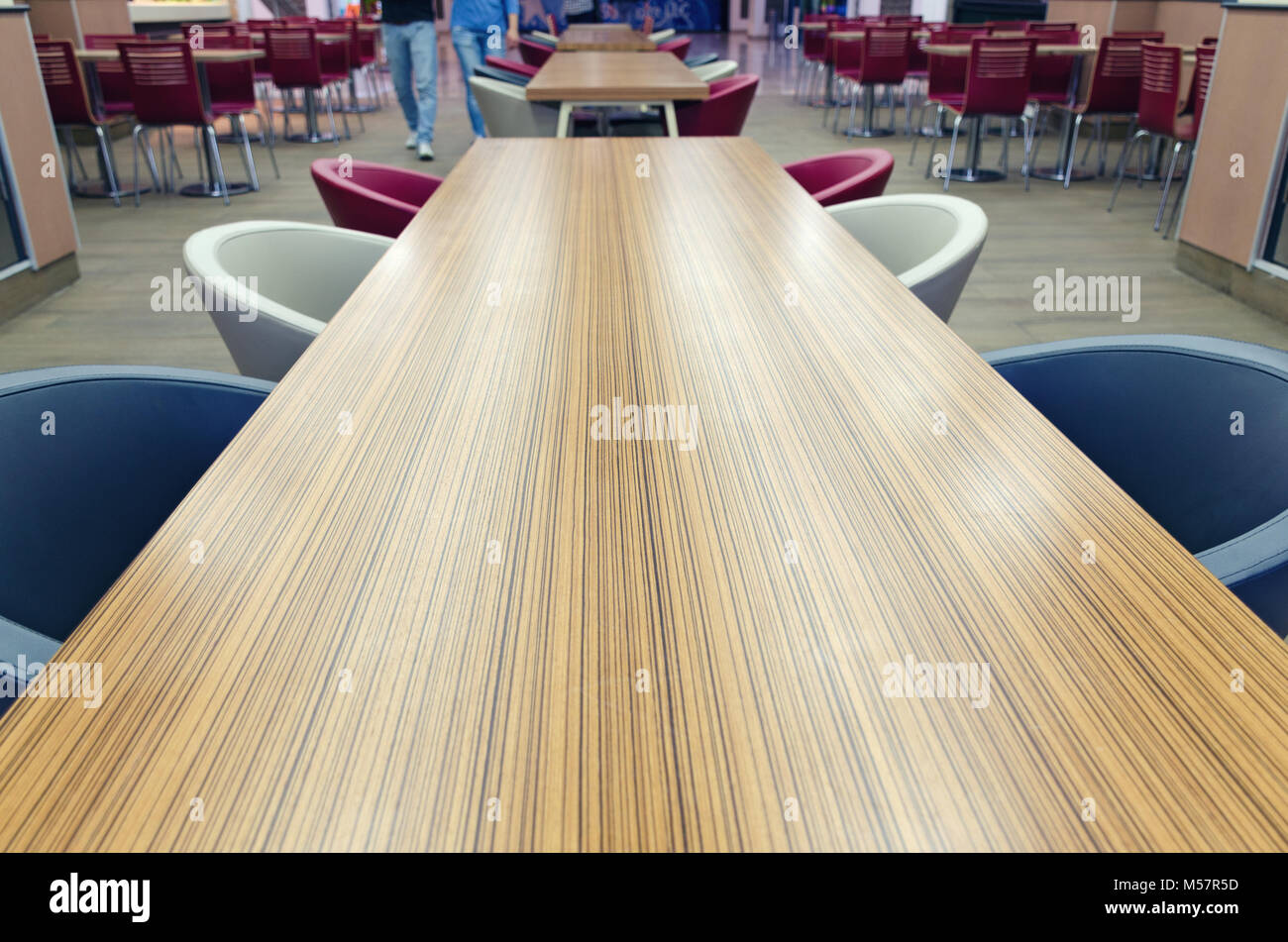 Blick von oben auf die Holz- lange gelb-braunen Tisch mit blauen und weißen Stühlen. Details der Cafe im Einkaufszentrum. Leere Platz für Text. Stockfoto