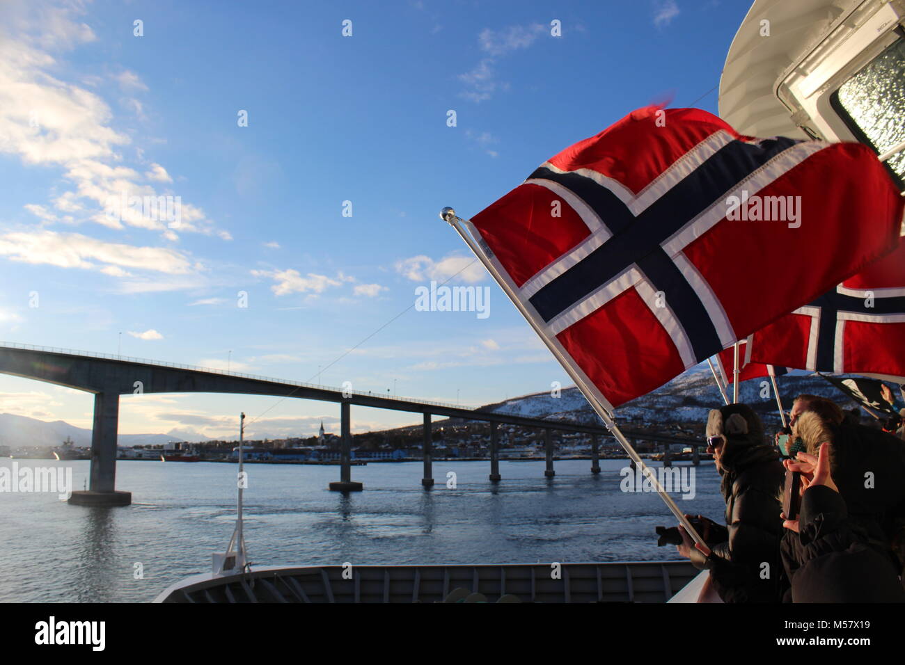 Kreuzfahrtpassagiere winken die norwegische Flagge und Fotografieren wie die Hurtigruten MS Trollfjord fährt die Brücke an Vesteralen Stockfoto