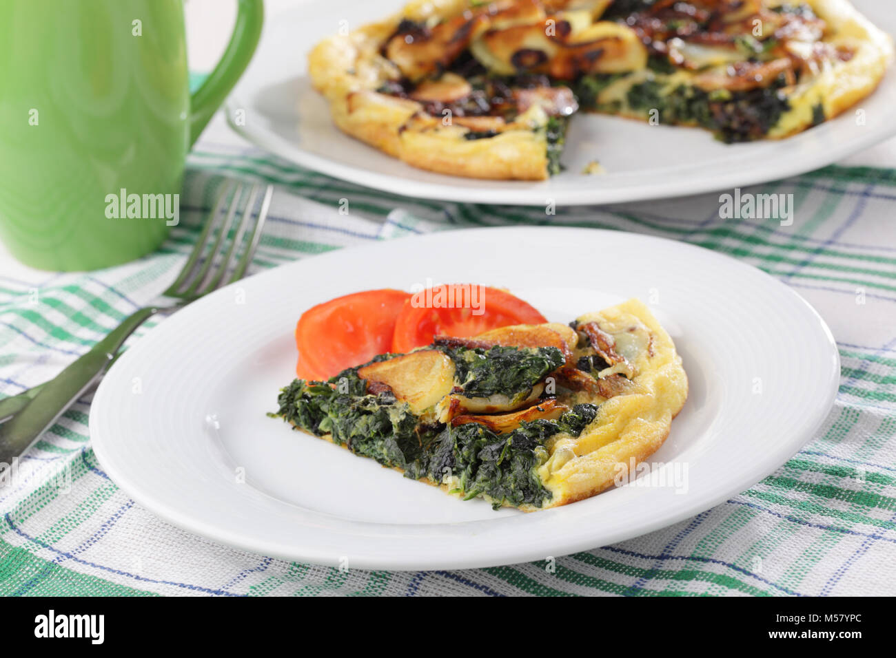 Frittata mit Spinat, Kartoffeln und Tomaten auf weiße Platte Stockfoto