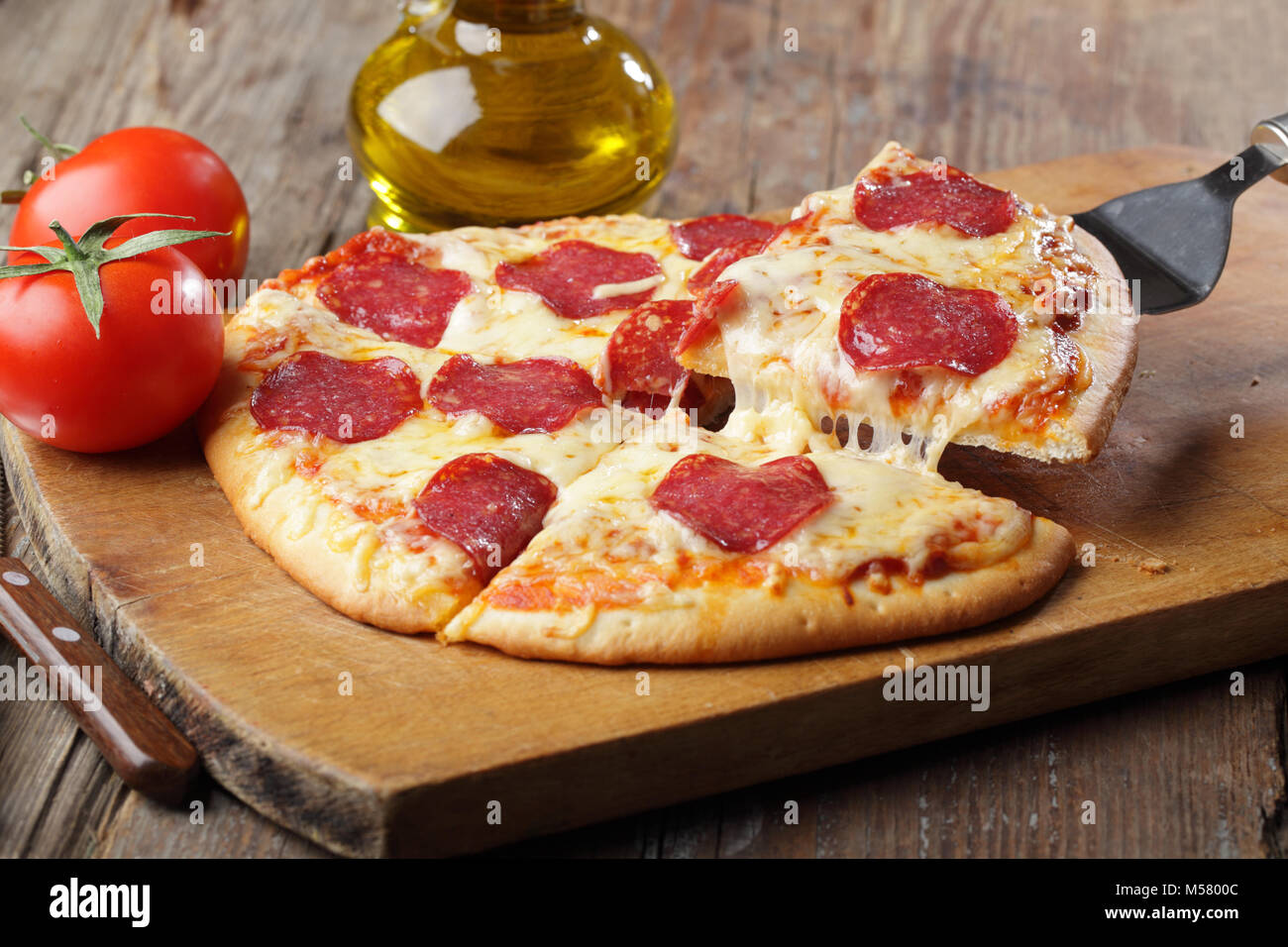 Pizza mit Salami und Käse auf einem Schneidebrett Stockfoto