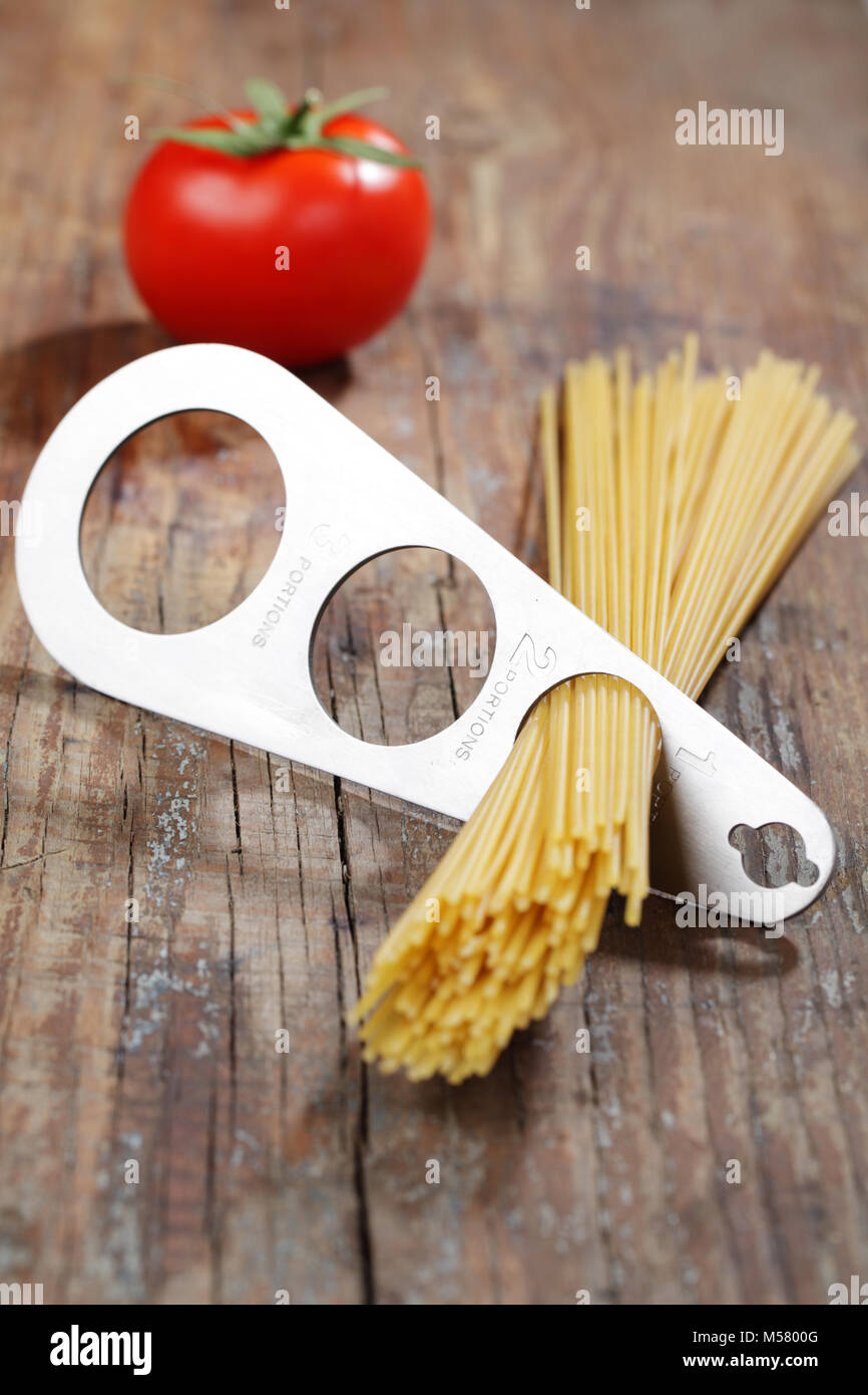 Spaghetti Portionierer, Spaghetti, und Tomaten auf einer hölzernen Tisch Stockfoto