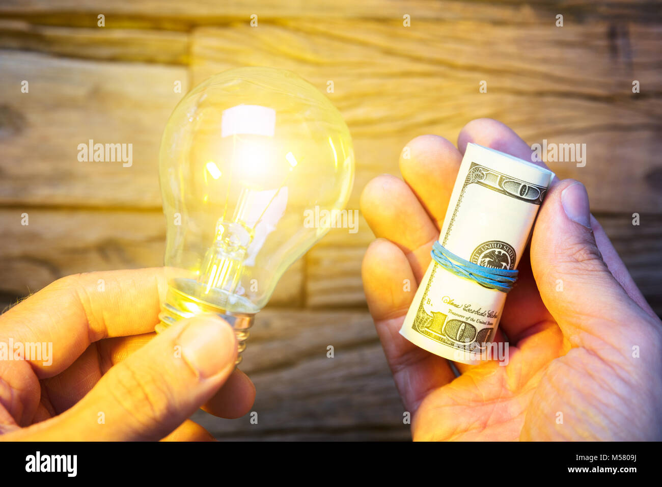 Nahaufnahme der Hände halten Dollar Noten und leuchtende Glühbirne Stockfoto