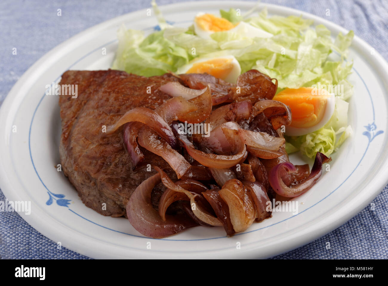 Rindersteak mit gerösteten Zwiebeln und Salat Stockfoto