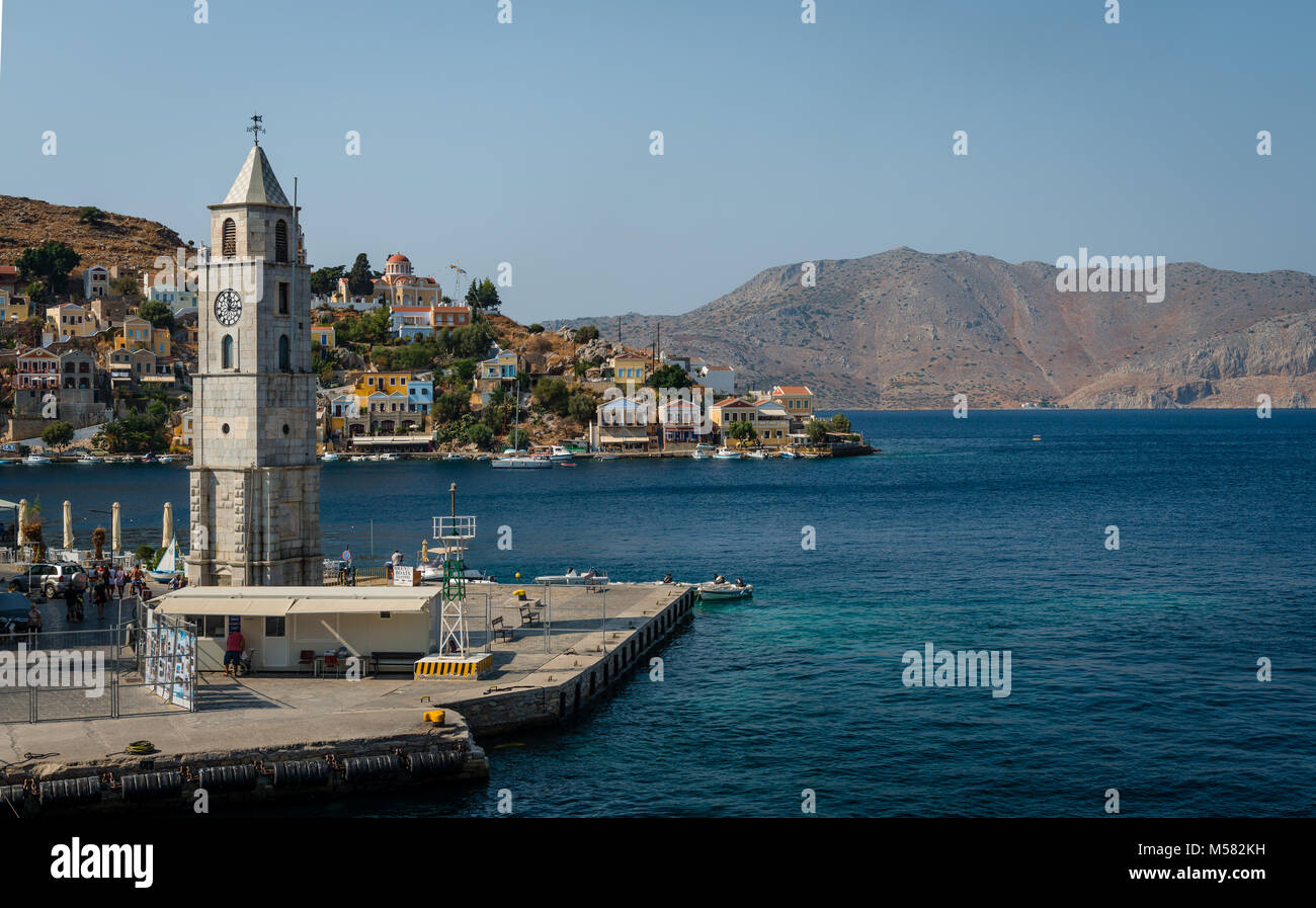 Der Uhrturm und die Einfahrt in den Hafen von Symi (Simi), eine kleine Insel der Dodekanes in Griechenland. Stockfoto