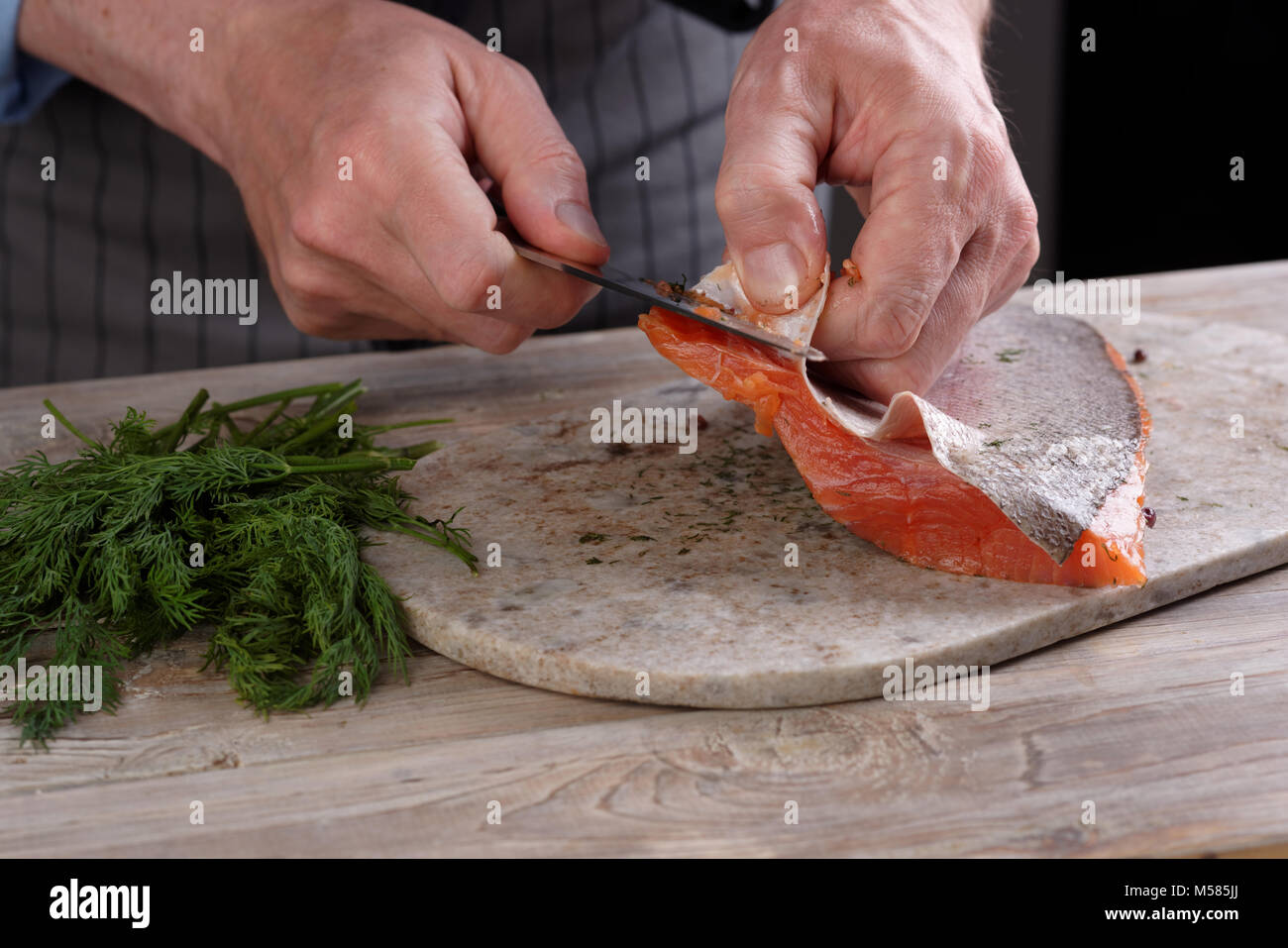 Kochen entfernen Haut von gesalzenen Lachs filet auf einem Schneidebrett Stockfoto