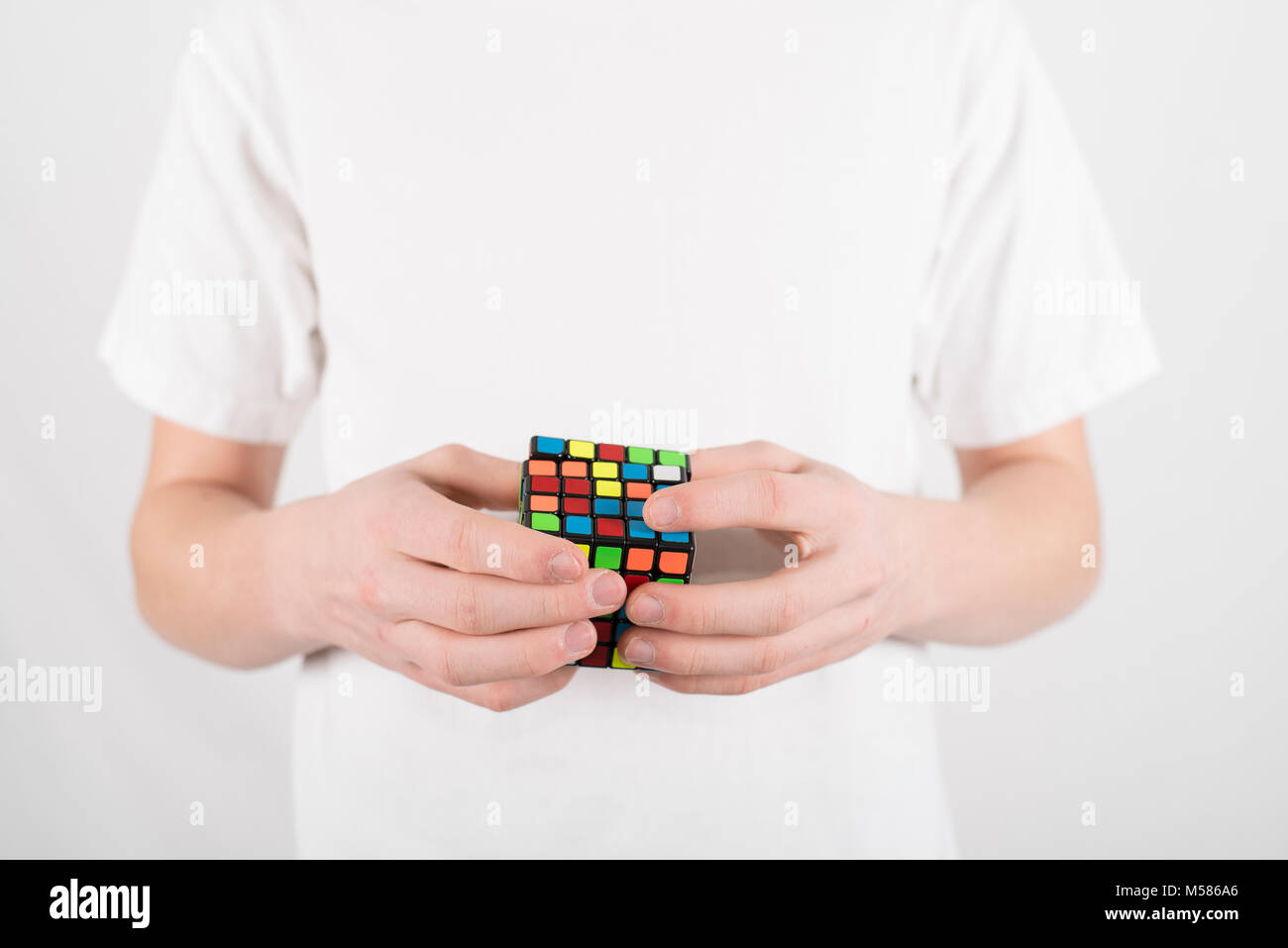 Teenager Geschwindigkeit Lösung 5 x 5 Würfel Puzzle im weißen T-Shirt mit  weissem Hintergrund Stockfotografie - Alamy