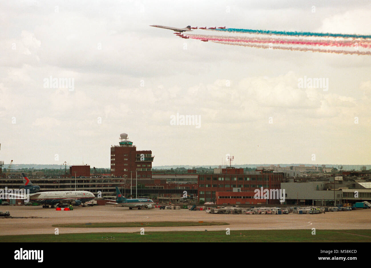 Einen British Airways Concorde führt die Royal Air Force Red Arrows Anzeige Squadron, wie Sie über London Heathrow Flughafen, der feiert sein 50 annniversary war Fliegen. Stockfoto