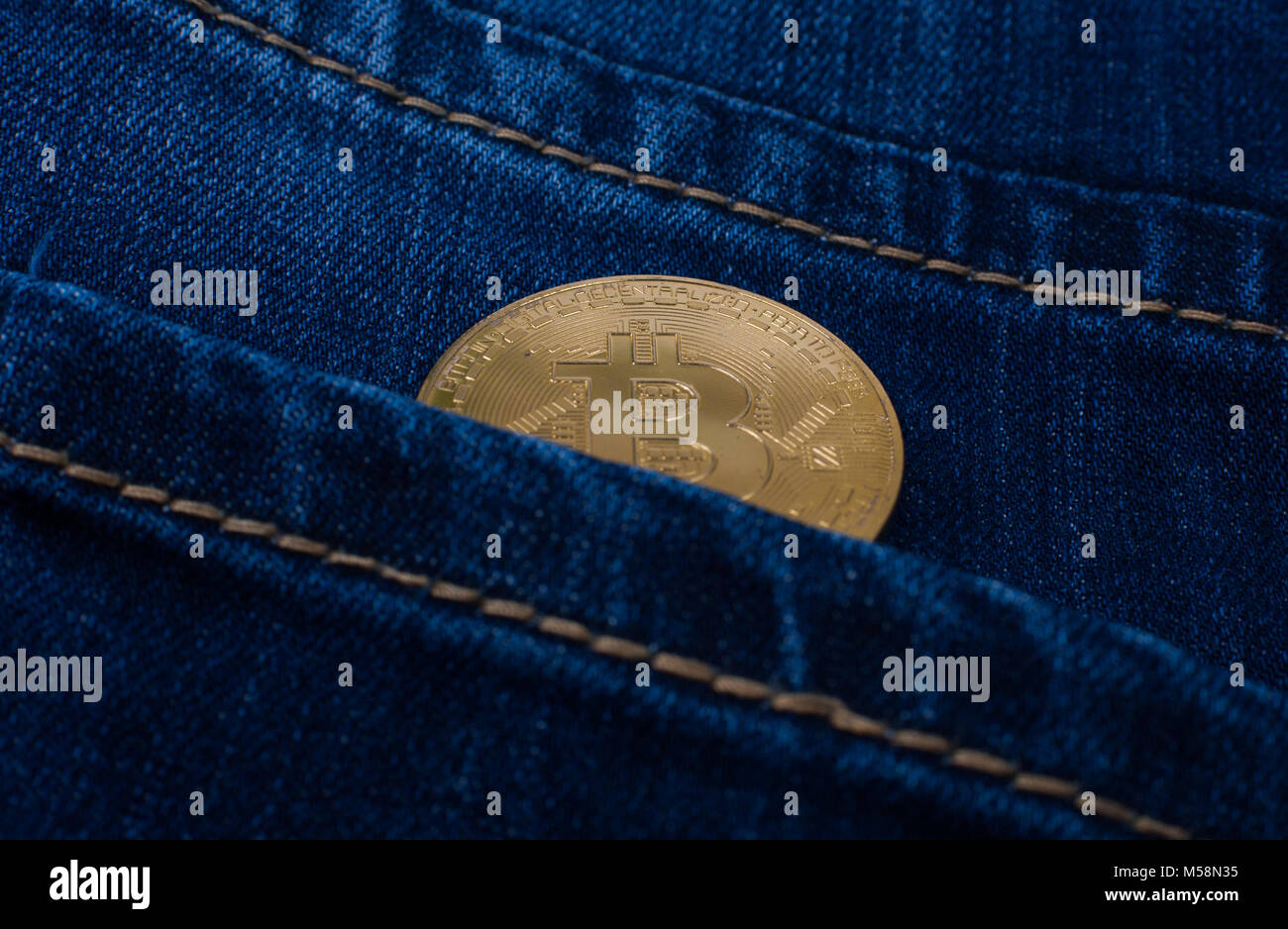 Bitcoin gold Münze in der Tasche der blauen Jeans. Stockfoto