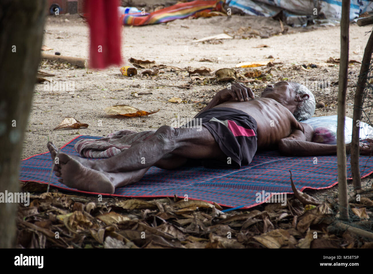 Ältere, unterernährte asiatischer Mann liegen am Strand schlafen Stockfoto