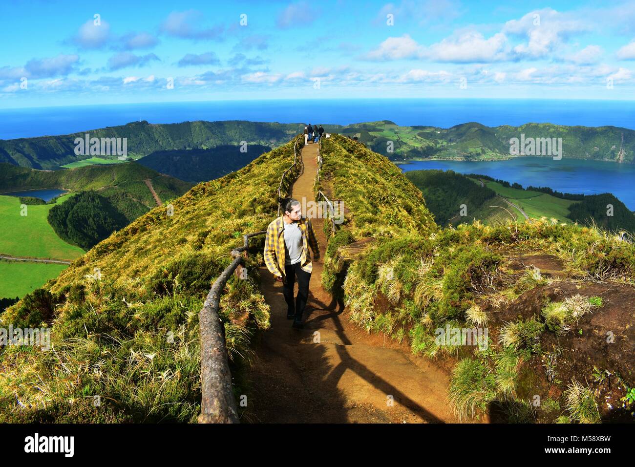 Reisenden zu Fuß in einen schmutzigen Weg in Tha oben auf einem Berg, mit Blick über eine Lagune volcaninc, Berge, Meer und Himmel. Stockfoto