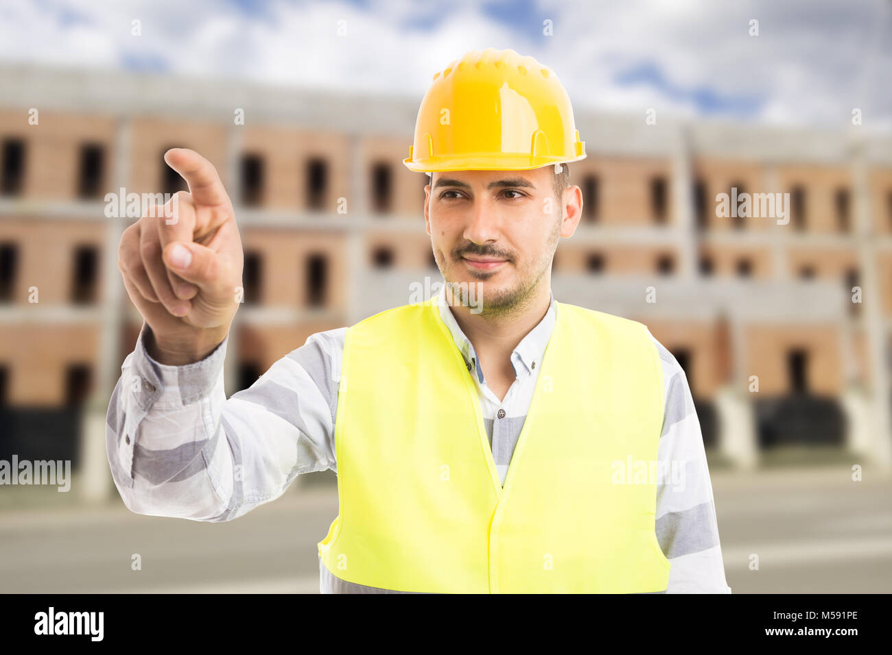 Zuversichtlich Architekt oder Ingenieur berühren unsichtbaren transparenten Display mit Zeigefinger outdoor mit einem Ziegelstein Gebäude im Bau behin Stockfoto