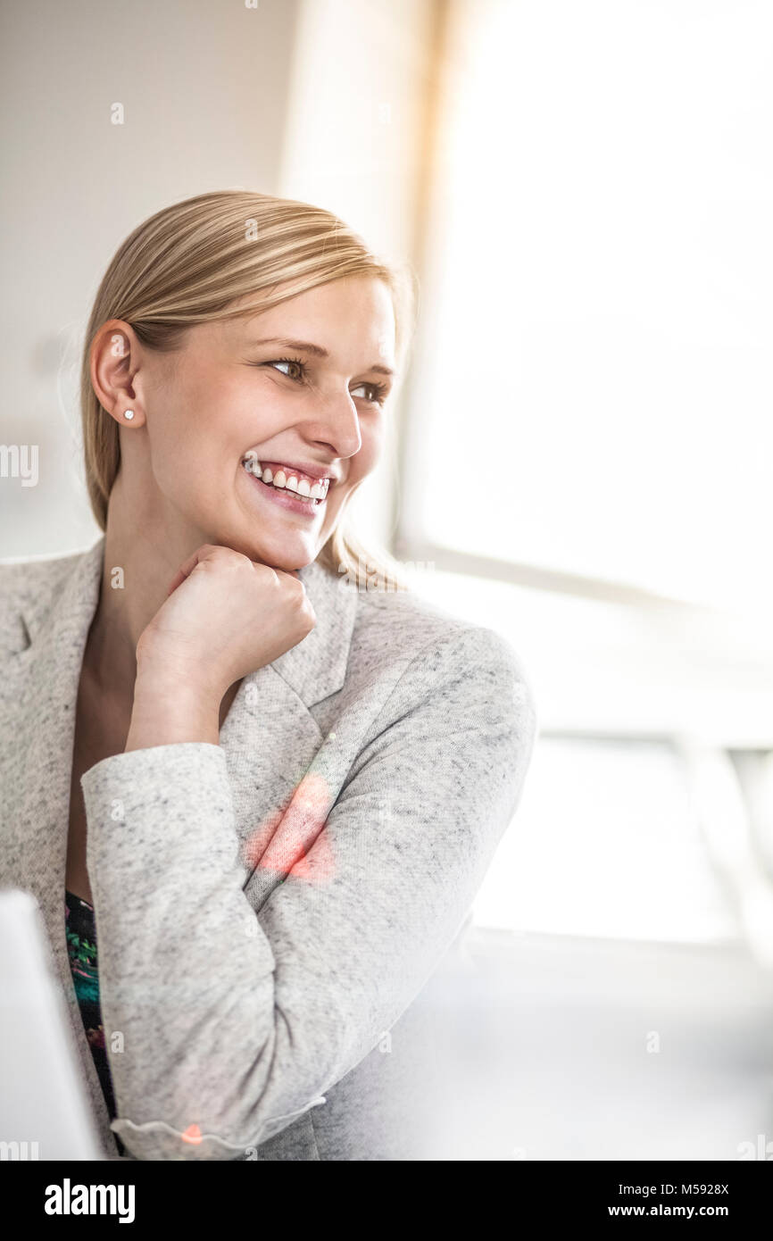 Lächelnden jungen Geschäftsfrau weg schauen in kreative Büro Stockfoto