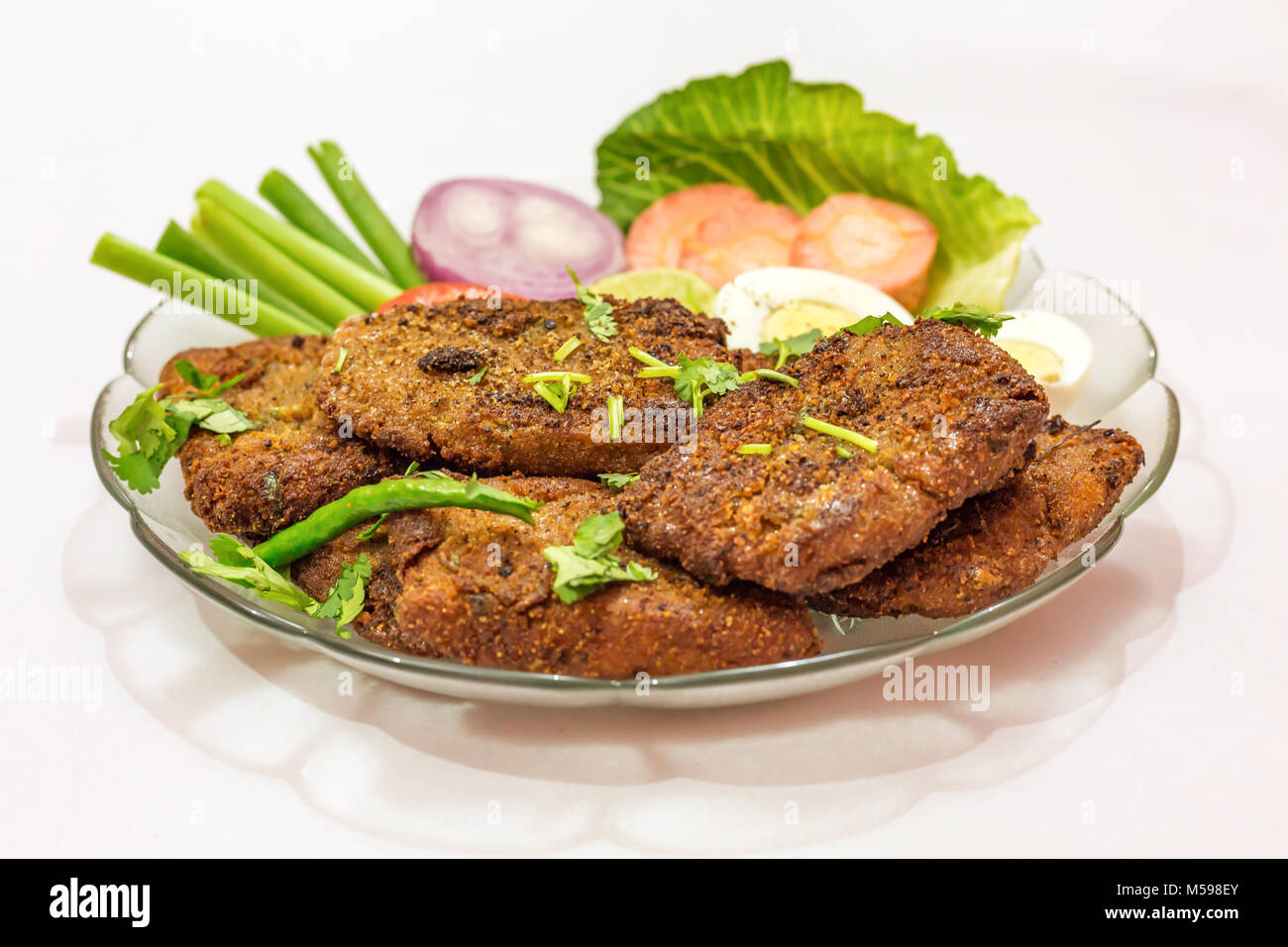 Leckere indische Bengali starter Gericht knusprige bhetki Fisch braten, garniert mit Bohnen mit Scheiben von Ei, Tomate, Karotte und Zwiebel. Stockfoto