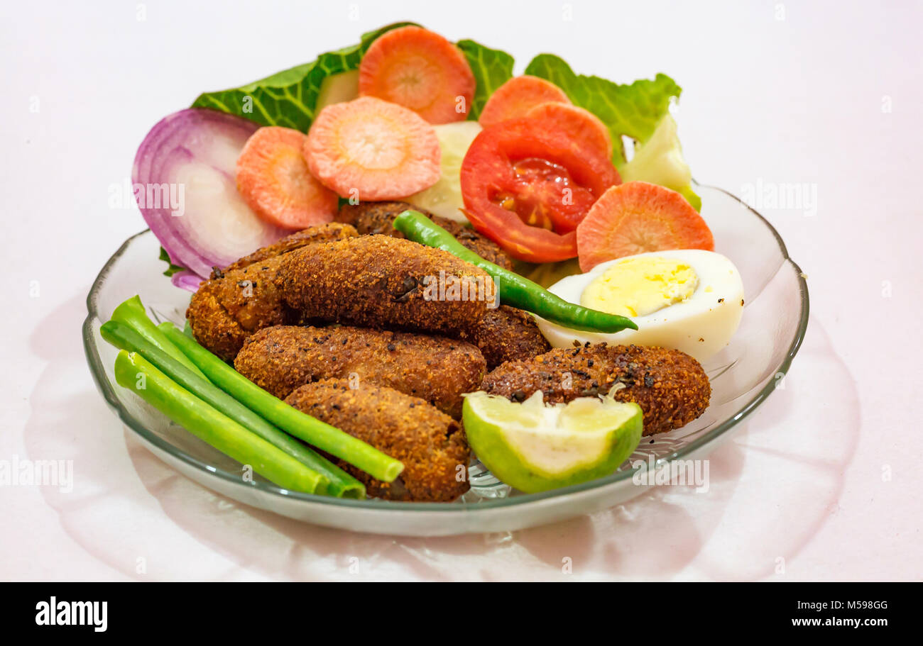 Knusprig frittierte Fisch finger Indischen starter Teller garniert mit Bohnen mit Scheiben von Ei, Tomate, Karotte und Zwiebel Stockfoto