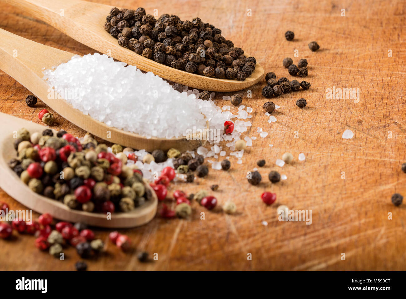 Löffel mit Salz und Pfeffer - Fokus auf schwarze Pfefferkörner Stockfoto