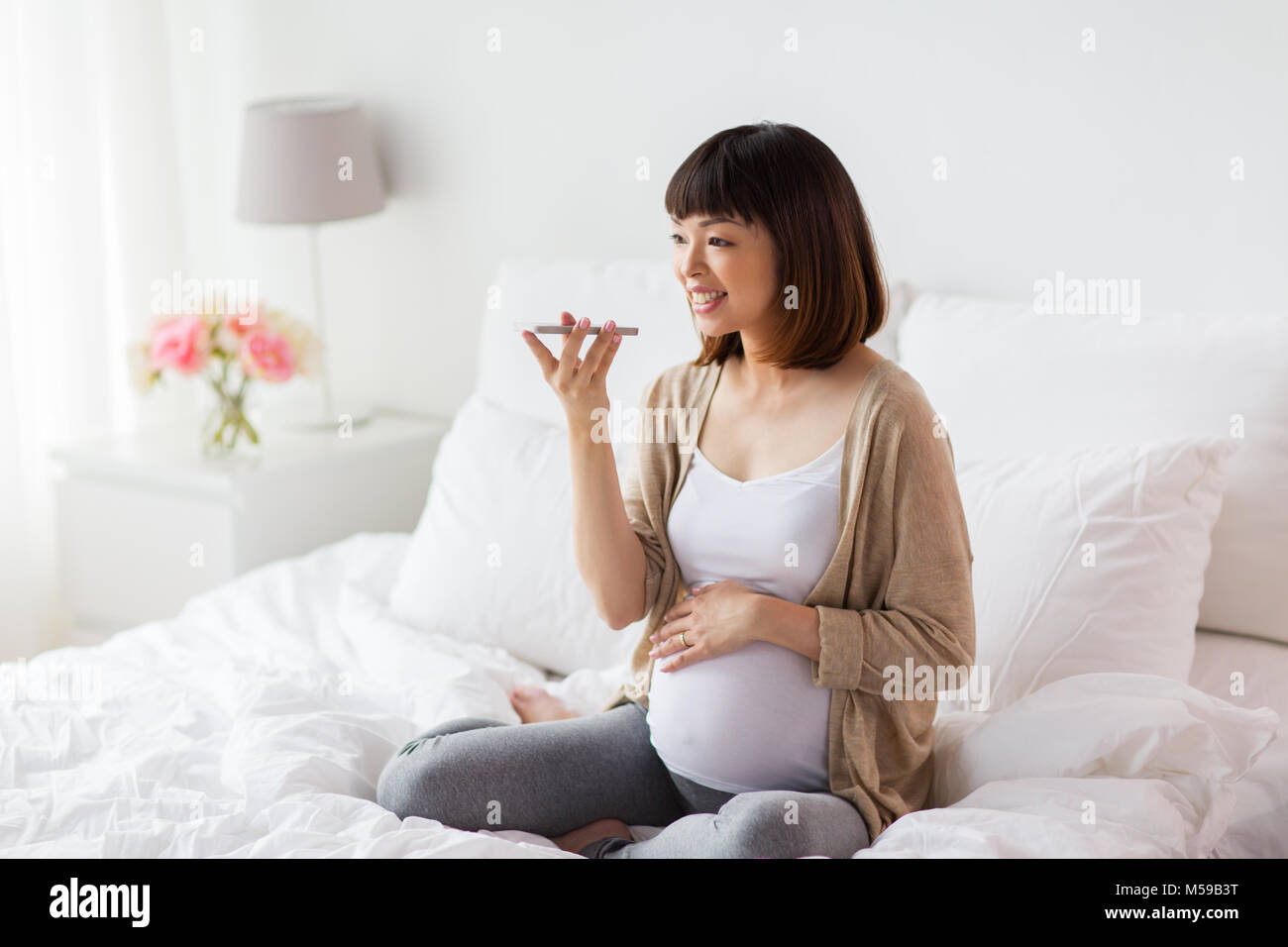 Schwangere Frau mit Voice-Recorder auf smartphone Stockfoto