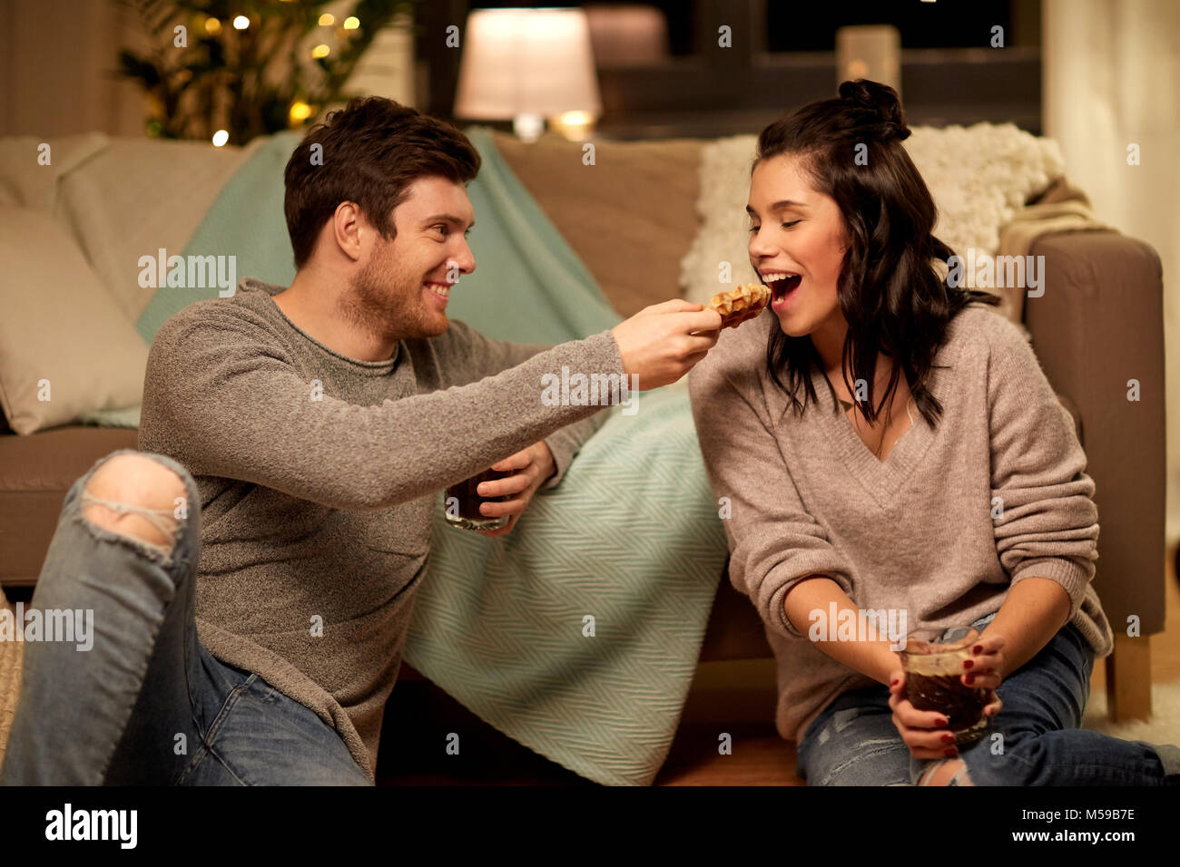 Glückliches Paar essen Waffeln mit Kakao zu Hause Stockfoto