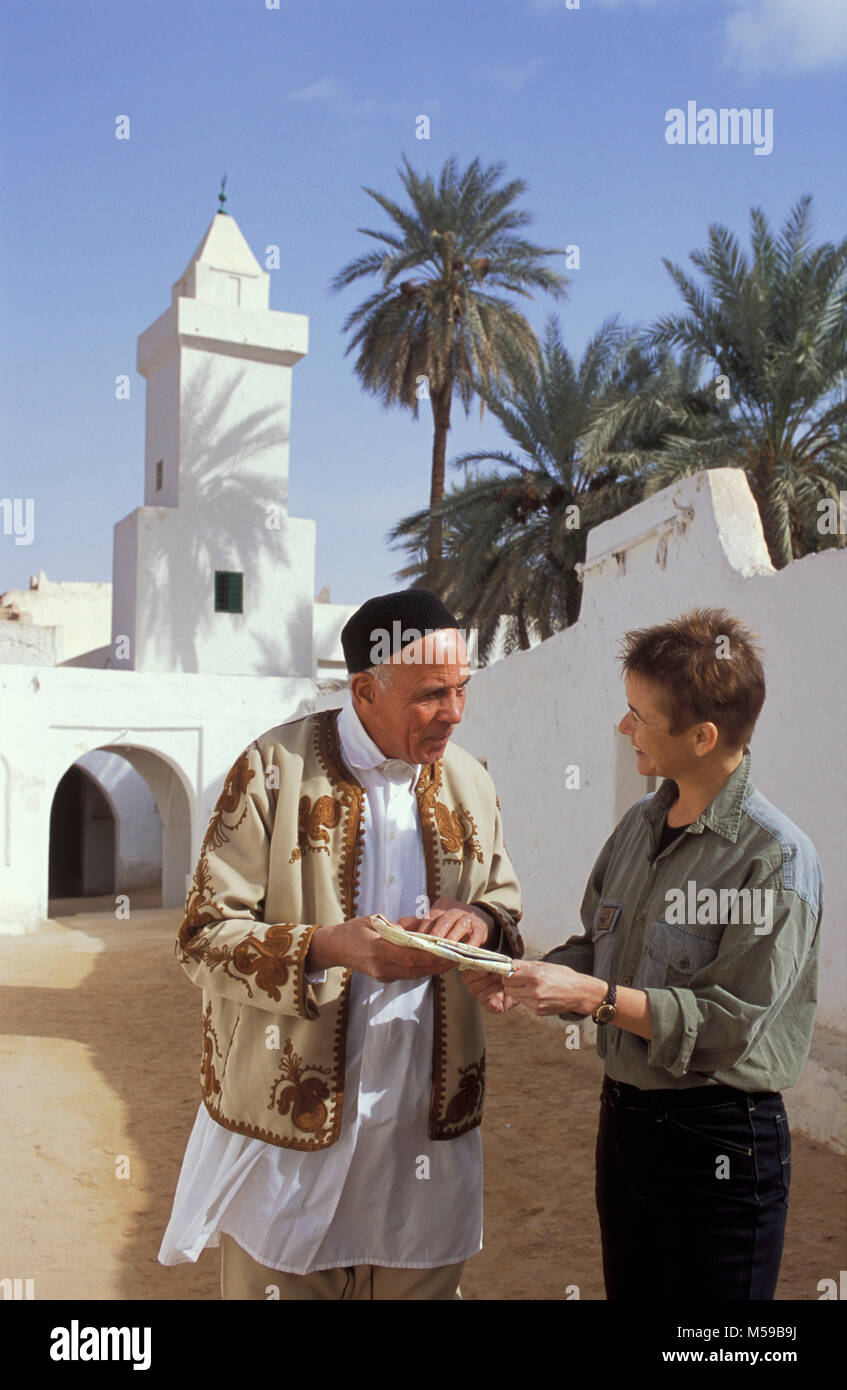 Libyen. Ghadames Oase. Sahara. Alte Stadt. Unesco-Weltkulturerbe. Lokale Berber mann Richtung zu geben, Frau mit Karte. Minarett der Moschee. Stockfoto