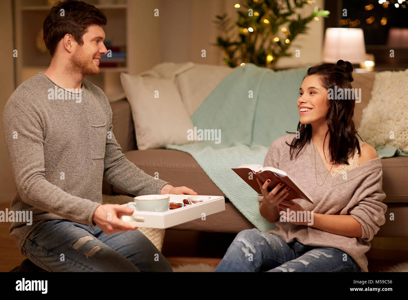 Glückliches Paar mit Buch und Essen zu Hause Stockfoto