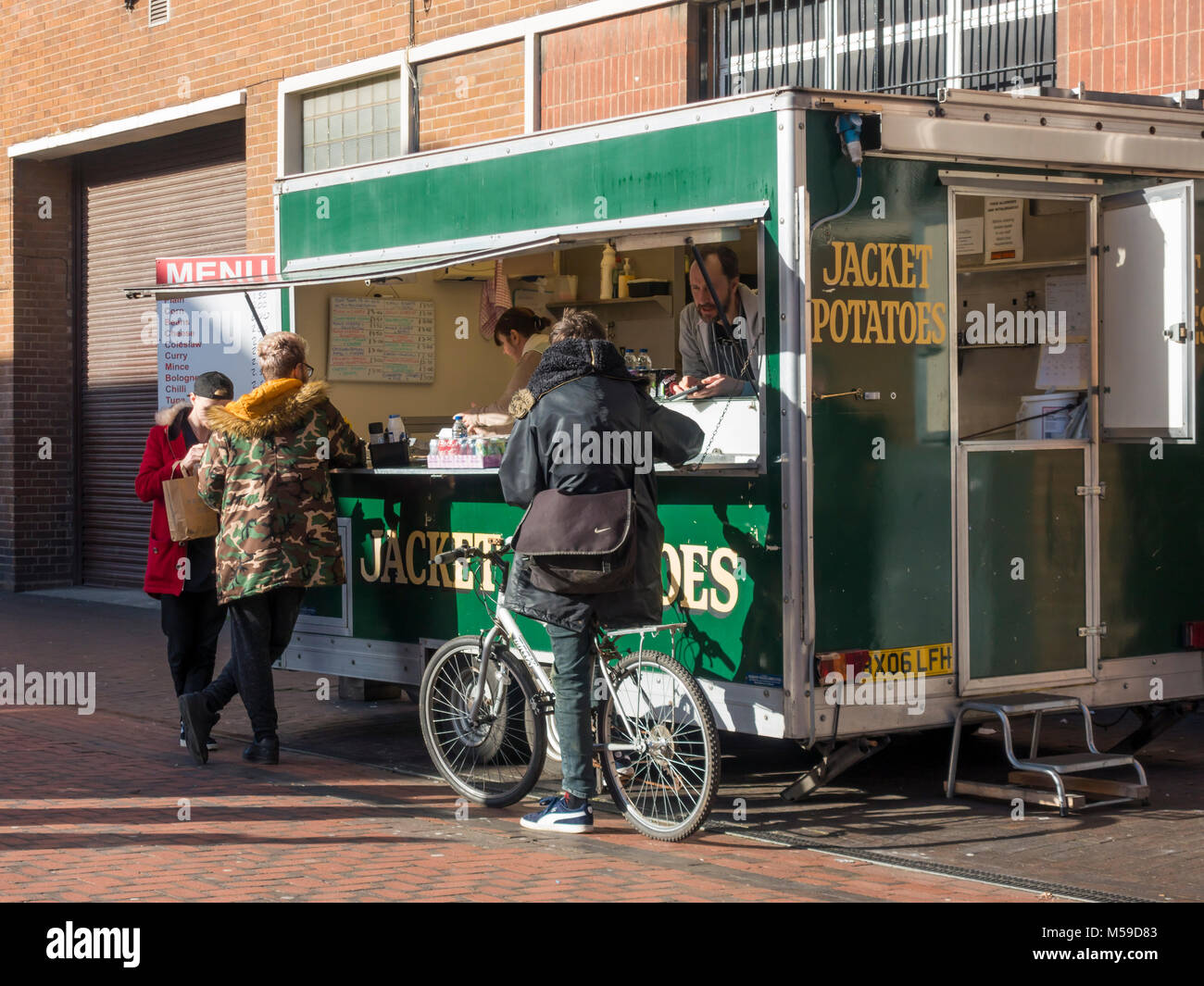 Eine Warteschlange von Menschen essen zu einem Jacke Kartoffel essen Stall in Gilkes Straße Middlesbrough auf einem anstrengenden Einkaufstag Stockfoto