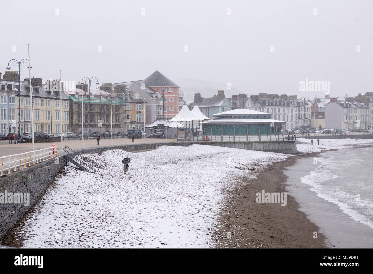 Eine Ansicht von Aberystwyth Strand und Meer Eigenschaften entlang der Promenade bei Schneefall im Winter Stockfoto
