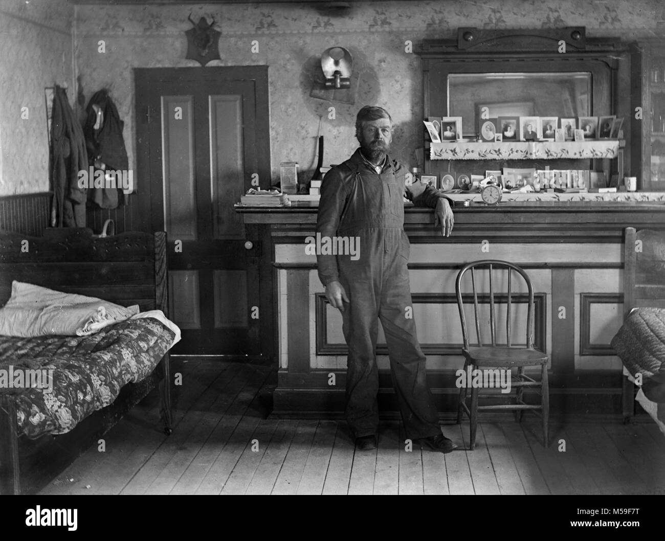 Single Mann steht in, was scheint, ein 1-Zimmer Apartment werden aus einer Taverne umgewandelt, ca 1900. Stockfoto