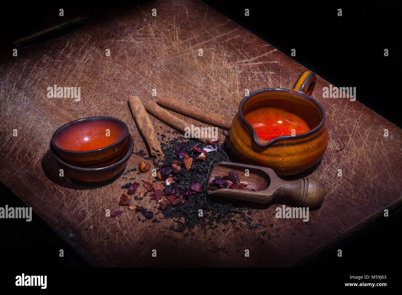 Teeblätter und Aromen mit Zubehör für Tee auf Holzbrett Stockfoto