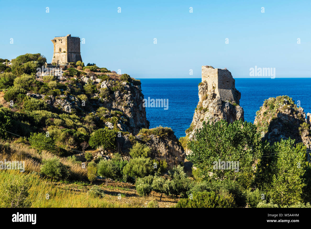 Klippen an der Küste mit den mittelalterlichen Türmen der Burg im Sommer in Scopello in der Nähe von Castellammare del Golfo auf Sizilien, Italien Stockfoto