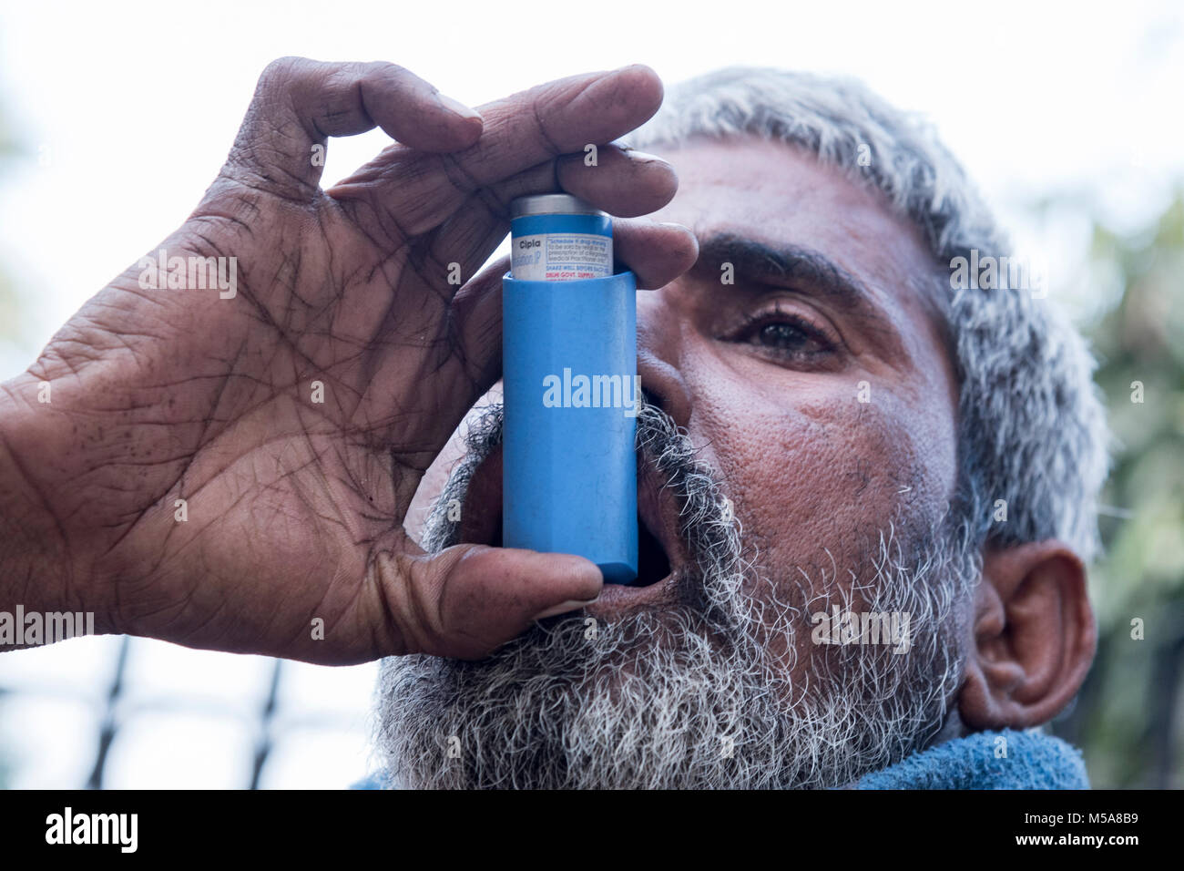 Porträt eines armen Inder, die Erleichterung von Asthma Inhalator zu erhalten Stockfoto