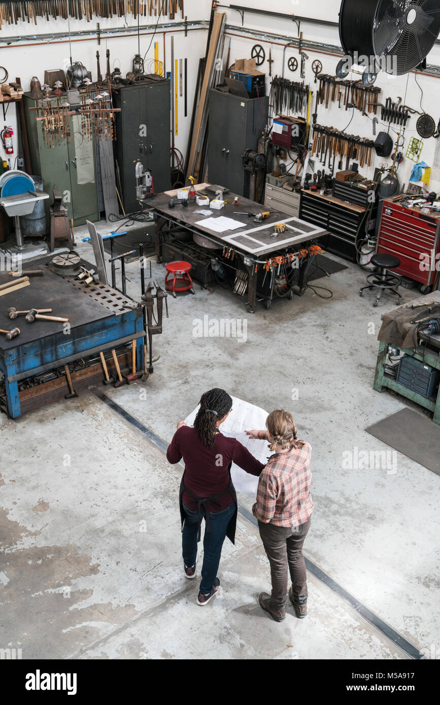 Hohe Betrachtungswinkel von zwei Frauen, die in der Metallwerkstatt, die den technischen Entwurf. Stockfoto