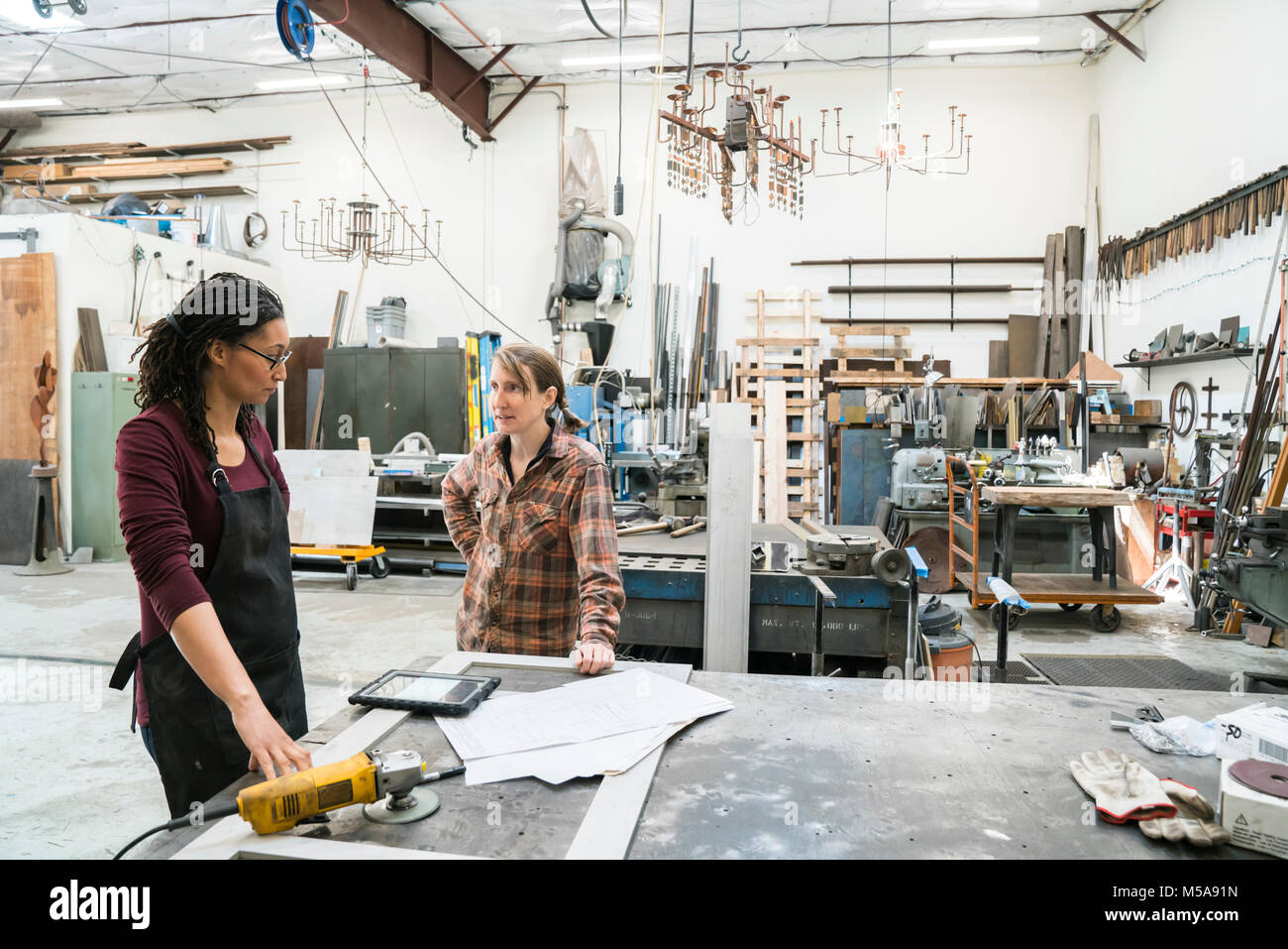 Zwei Frauen stehen an der Werkbank in der Metallwerkstatt. Stockfoto