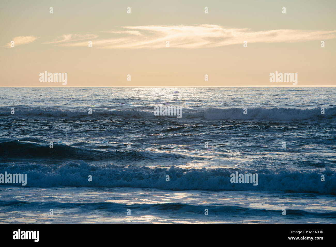 Meereslandschaft mit brechenden Wellen bei bewölktem Himmel bei Sonnenuntergang. Stockfoto
