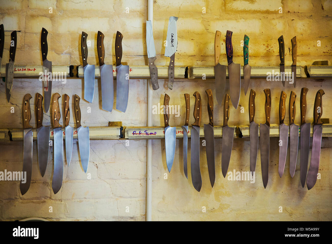 Messer mit geformten Holzgriff und eine Vielzahl von geformte Rotorblätter auf magnetische Messerhalter in einem Workshop. Stockfoto