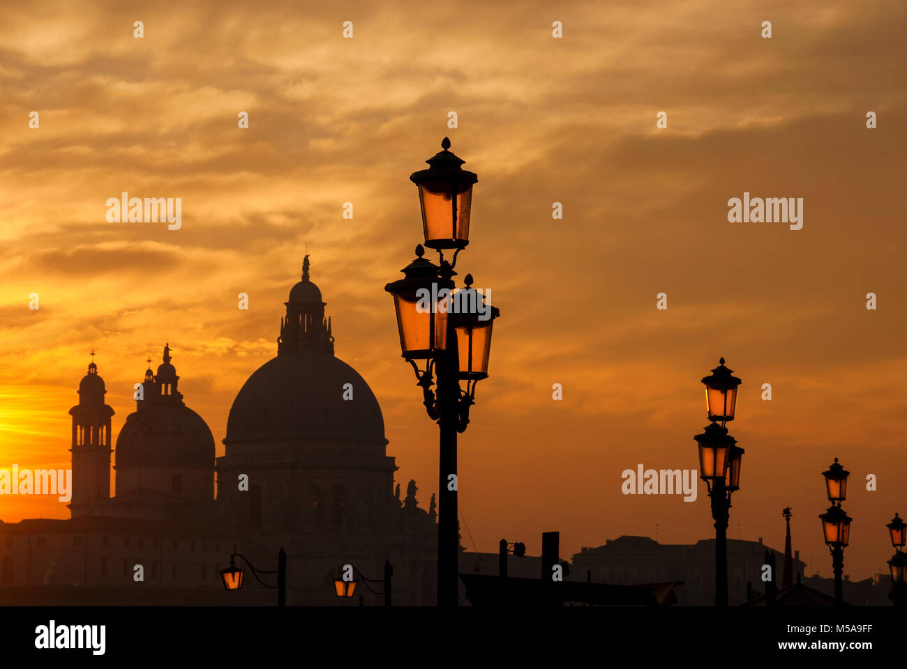 Venedig Sonnenuntergang mit alten Kuppeln, Lampe und Haze Stockfoto