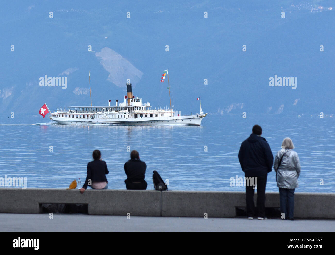 Die Menschen am Ufer am Genfer See in Lausanne mit Bootsfahrt auf dem Hintergrund. Stockfoto